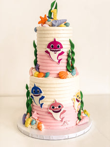 4-6" two tier cake with a white to pink ombre, and with baby shark print outs and details.