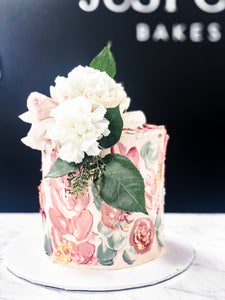 Size: 6" one tier. Icing exterior: white. Accents: white, greens, pinks.